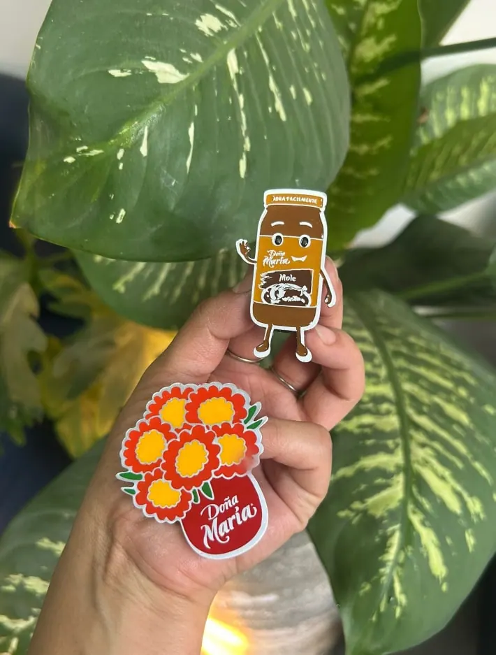 Pines de colores con ilustraciones, sostenidos en la mano