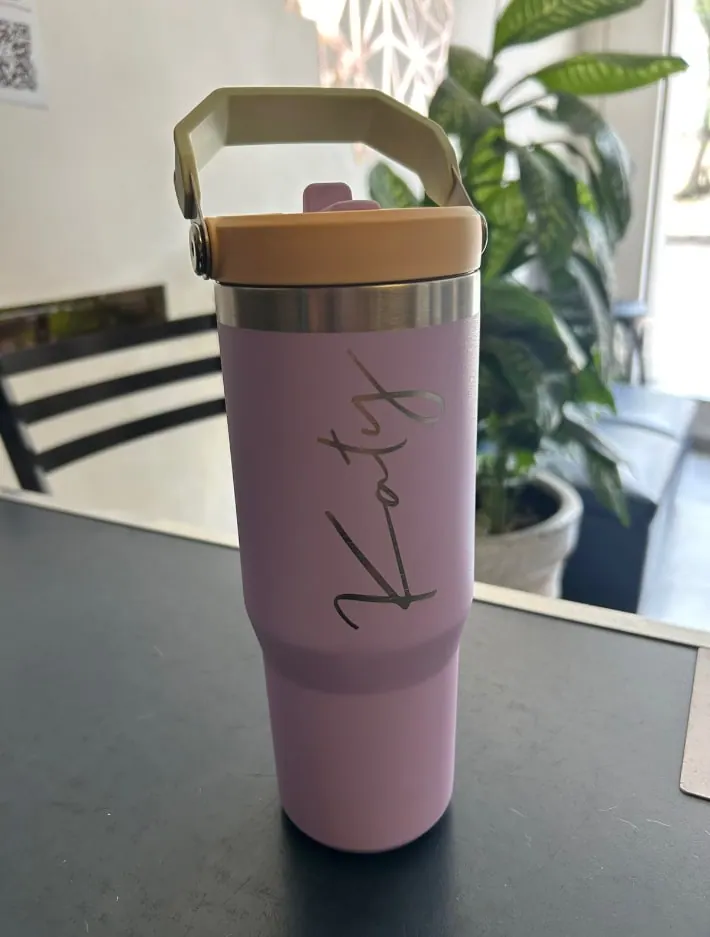 Termo rosa con asa y un nombre grabado