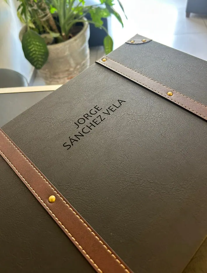 Carpeta de vinipiel negra con un nombre grabado
