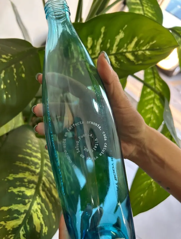 Botella de vidrio azul con texto grabado en círculo