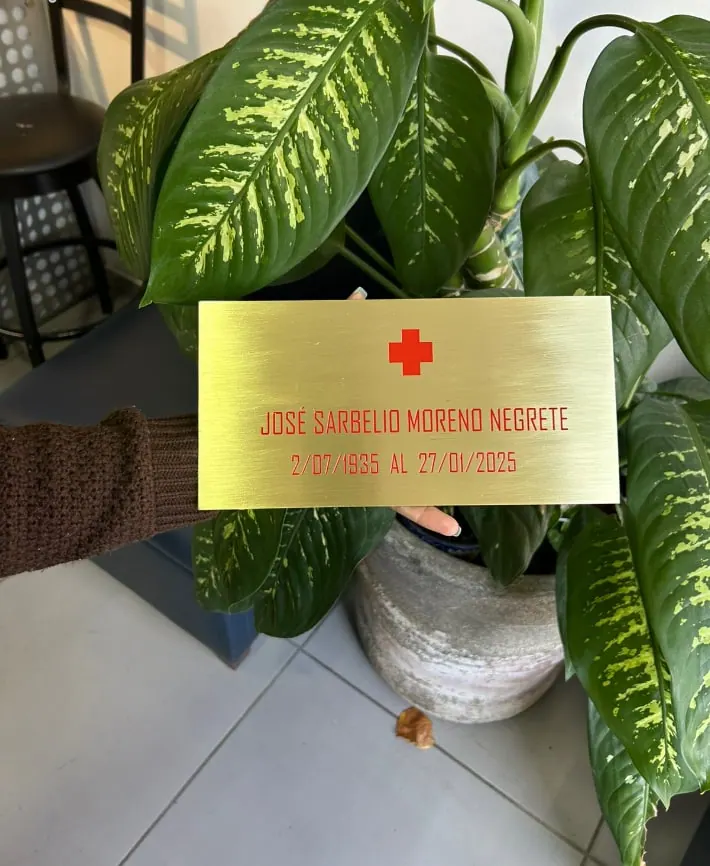 Placa dorada con nombre y una cruz roja grabados