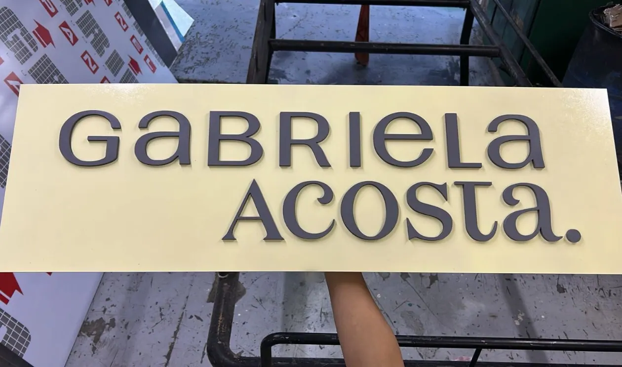 Letrero con un nombre en letras negras sobre fondo crema