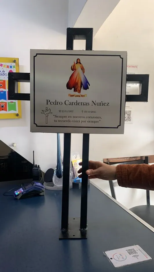 Placa conmemorativa con imagen religiosa sobre un soporte en cruz