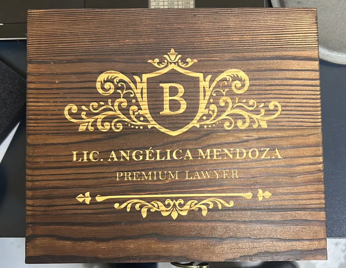 Placa de madera oscura con escudo y texto grabados en dorado