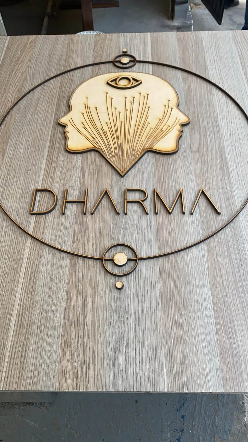Logotipo dorado cortado y montado sobre un panel de madera