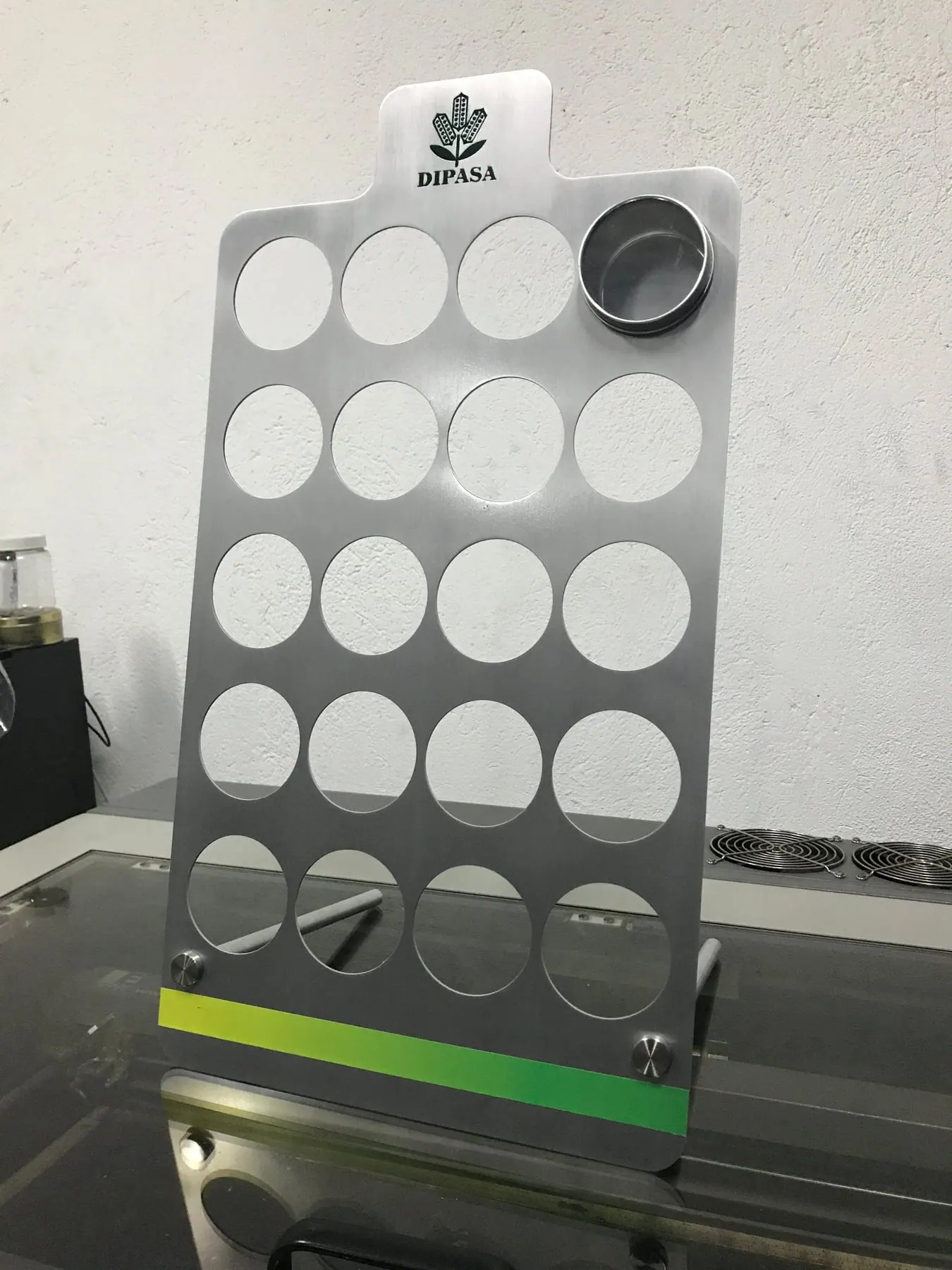 Panel de metal cepillado con perforaciones circulares para exhibir muestras